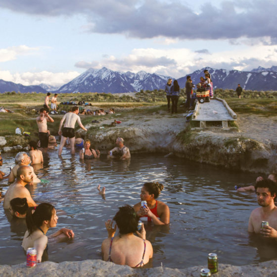 many people sitting in hot springs in the mountains